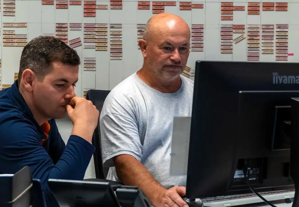 Zwei Mitarbeiter koordinieren Bauarbeiten am Computer