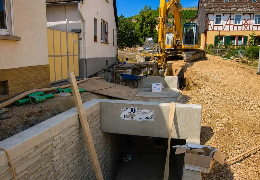 Bauarbeiten an einem Betondurchlass zwischen Wohnhäusern